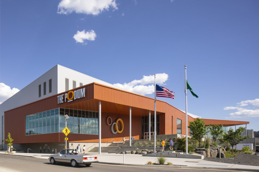 Photo of The Podium Powered by STCU building with an American flag waving in front of the building and blue sky behind it