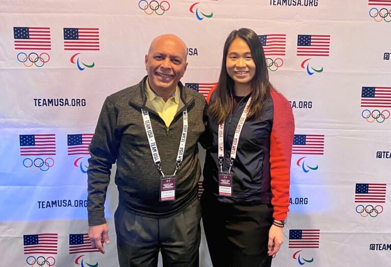 Photo of Dr. Rajeev Trehan and Jamie Subandhi standing next to each other. They are wearing Team USA clothing and lanyards and are smiling. The background has the USOPC logos and says TeamUSA.org